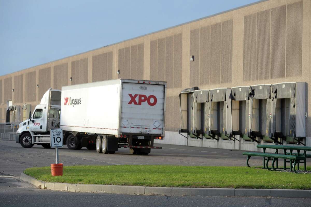 An XPO Logistics truck in November 2019 outside the Long Beach Boulevard warehouses in Stratford, Conn., leased by Amazon for a new distribution center. With the ongoing growth in online commerce, Greenwich-based XPO has grown into one of the world’s largest shipping companies with some 100,000 workers, even as it embraces emerging robotic technologies.