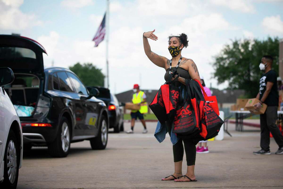Victoria Toledo motions for cars to approach the distribution area during a food giveaway at Bush Elementary on Saturday, June 6, 2020.