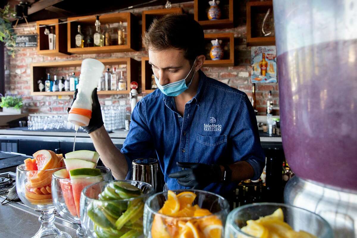 Bar manager Marc Pontavella wears a mask and gloves while making a cocktail for a customer at Teleferic Barcelona in Walnut Creek, Calif. Tuesday, June 9, 2020. They Bay Area is opening at a fairly fast pace, with Contra Costa County announcing plans this week to reopen indoor dining and hair salons soon, while it reports near-record new cases.