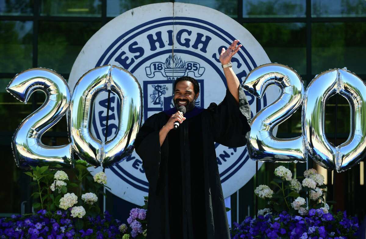 Principal Stafford Thomas Jr welcomes the Class of 2020 graduates as they ride in a motorcade to Staples High School for a drive-through commencement ceremony Friday, June 12, 2020, in Westport, Conn.
