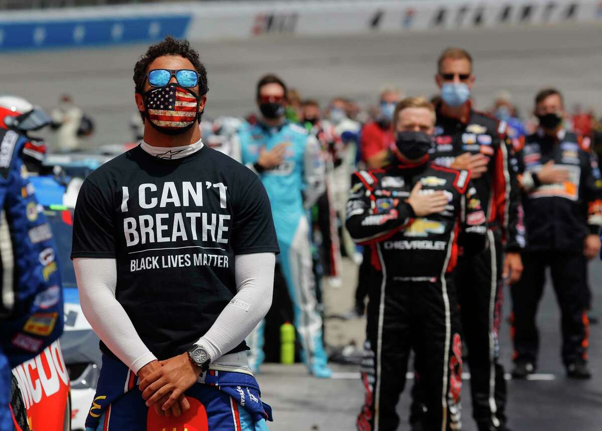 HAMPTON, GEORGIA - JUNE 07: Bubba Wallace, driver of the #43 McDonald's Chevrolet, wears a "I Can't Breath - Black Lives Matter" T-shirt under his fire suit in solidarity with protesters around the world taking to the streets after the death of George Floyd on May 25 while in the custody of Minneapolis, Minnesota police, stands during the national anthem prior to the NASCAR Cup Series Folds of Honor QuikTrip 500 at Atlanta Motor Speedway on June 07, 2020 in Hampton, Georgia. (Photo by Chris Graythen/Getty Images) *** BESTPIX ***