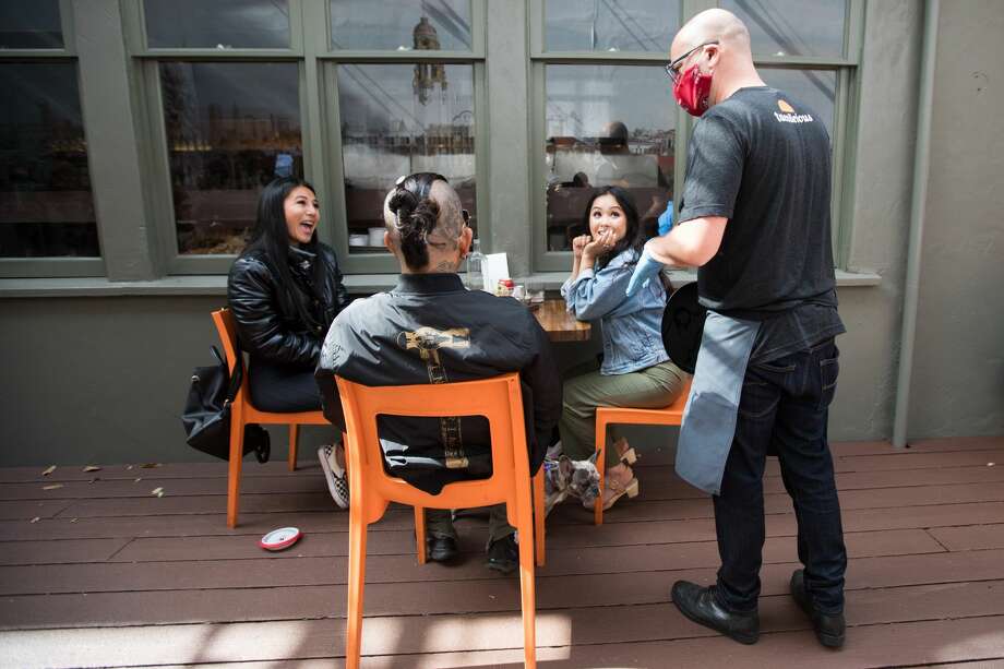 Server Daniel Erwin talks to some customers at Tacolicious on Valencia Street. The restaurant in San Francisco, Calif. started offering outdoor food service on June 12, 2020. Photo: Douglas Zimmerman/SFGATE / SFGATE