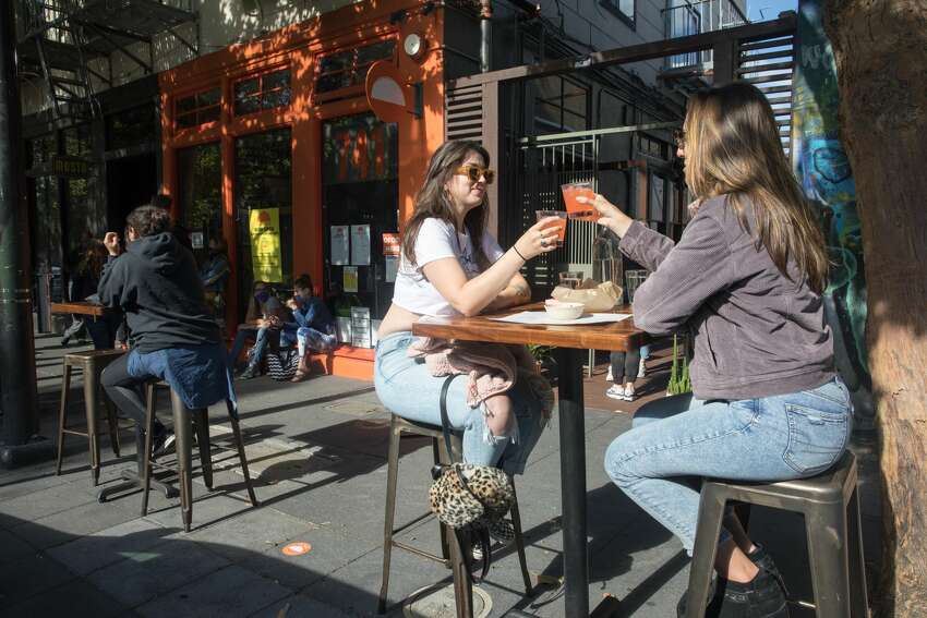(Left to right) Haylie Aitken and Rachel Pratley enjoy a margarita atTacolicious on Valencia Street in San Francisco, Calif.. The restaurant started offering outdoor food service on June 12, 2020..