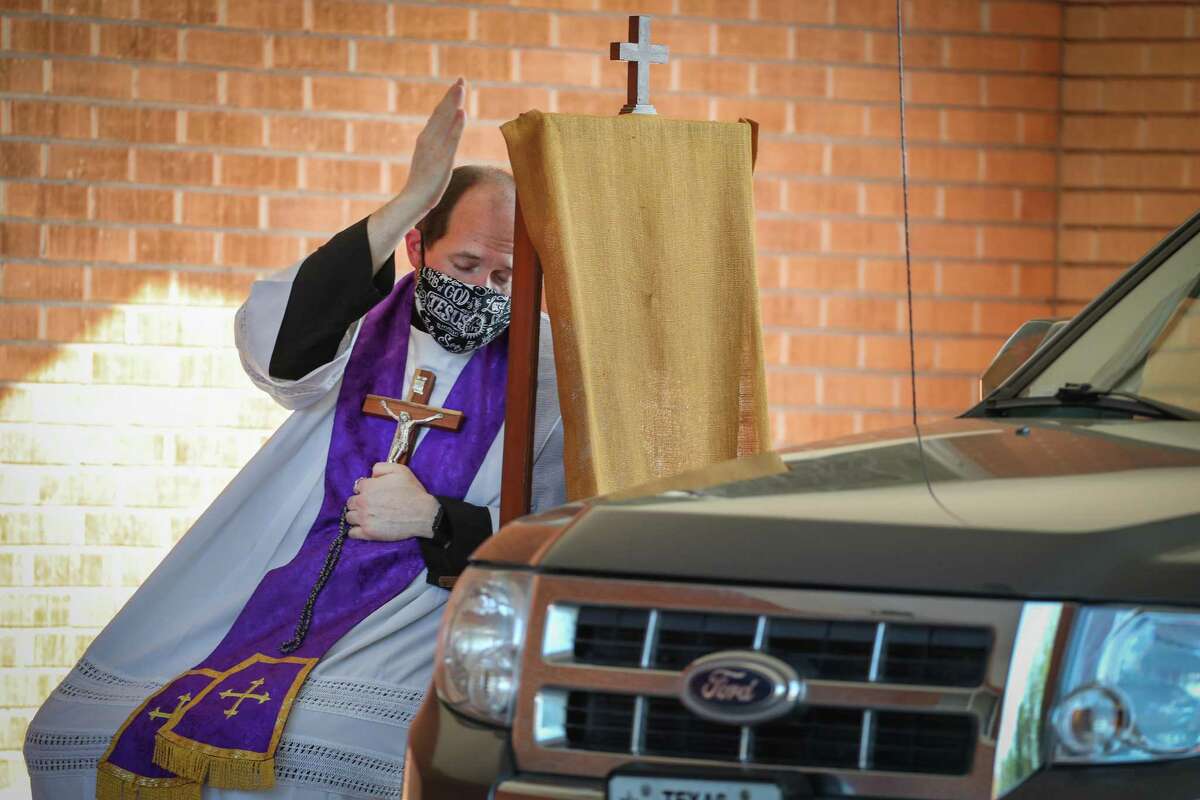 Father David Hust of St. Vincent De Paul Catholic Church hears confessions in the church parking lot in April. Faith leaders are exercising an abundance of caution in activities for their members.