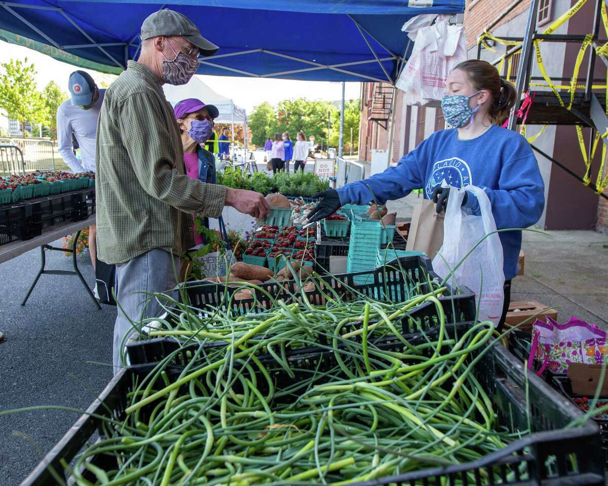 Rebecca Krees, of Bulich Creekside Farm, bags produce for Bob and Diane Speece at the Troy Waterfront Farmers Market, which returned to Riverfront Park on Saturday, June 13, 2020 with 43 vendors. The market returns April 3, 2021. (Jim Franco/Special to the Times Union.)