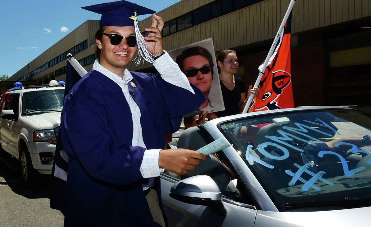 Graduates including Tommy McHugh arrive by motorcade at the Wilton High School commencement ceremony Saturday, June 13, 2020, in Wilton, Conn. The caravan followed a four-mile loop that went past Miller-Driscoll, Middlebrook and Cider Mill schools. Cars carrying the graduates and their families then entered Kristine Lilly Way from School Road and formed two lines that drove under the arch in front of the high school.