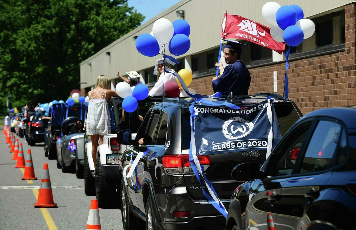 Graduates arrive by motorcade at the Wilton High School commencement ceremony Saturday, June 13, 2020, in Wilton, Conn. The last months of high school for the class were cut short due to quarantining at home during the coronavirus pandemic, so school officials set out to make graduation special for the students. Working with the town, they decided to hold a caravan parade to honor the class of 2020.