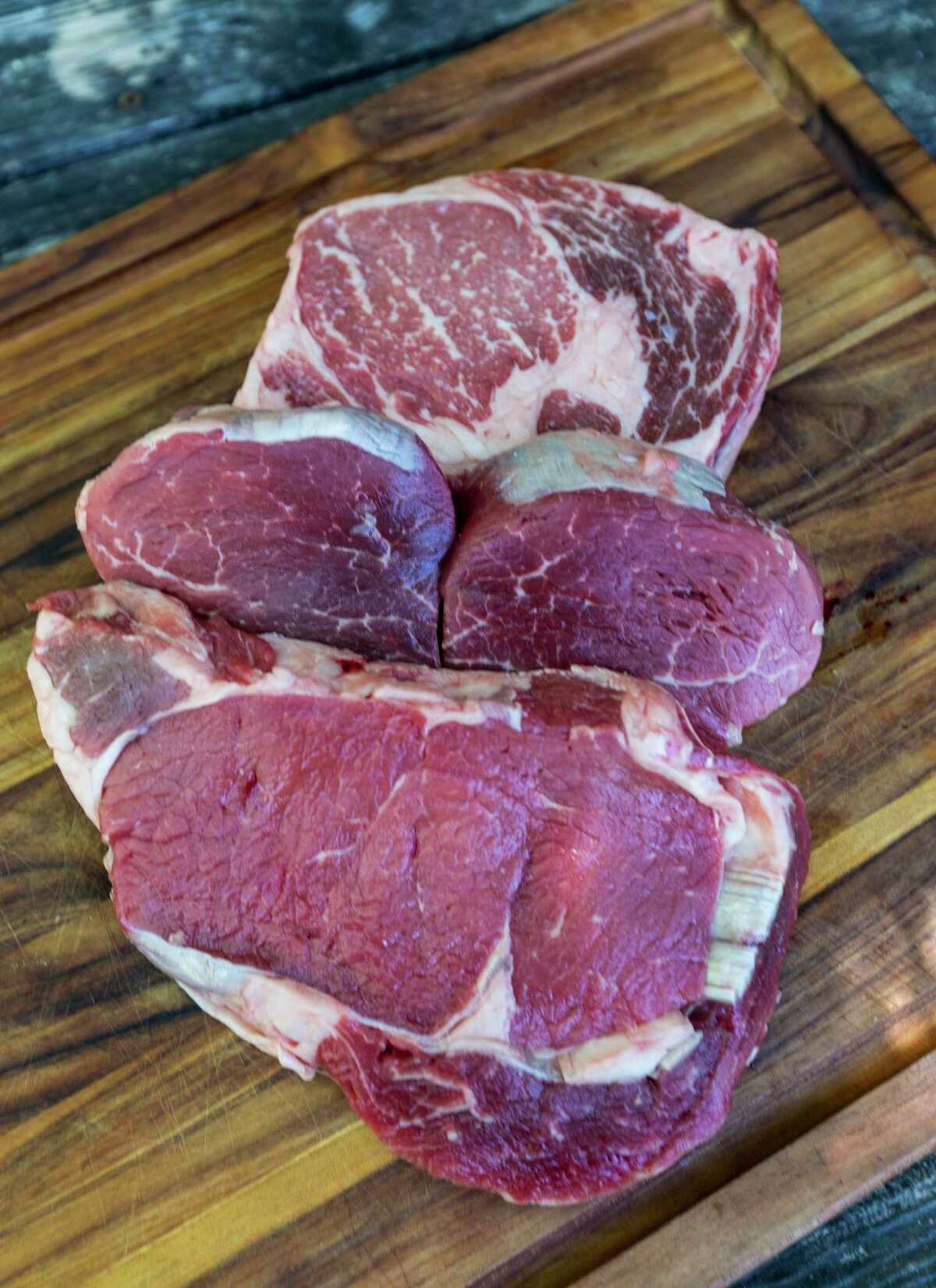 Steaks are graded based on their marbling. Pictured are (from front to back): select, choice and prime rib-eye steaks.