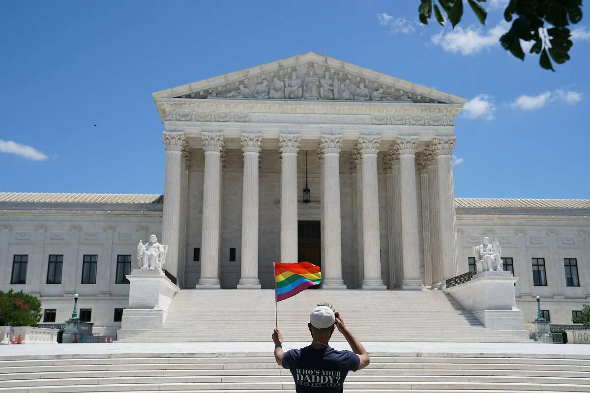 A person waves a rainbow flag in front of the Supreme Court in Washington, on Monday, June 15, 2020. The Supreme Court ruled Monday that a landmark civil rights law protects gay and transgender workers from workplace discrimination, handing the movement for L.G.B.T. equality a stunning victory. (Anna Moneymaker/The New York Times)