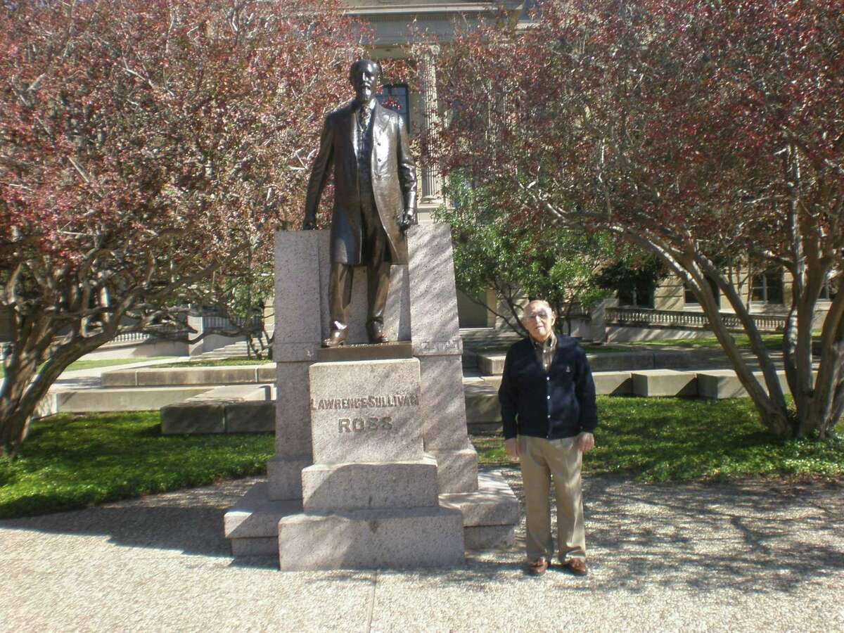 A former student at Texas A&M University poses before the statue of Lawrence Sullivan Sul Ross, one-time president of the school.