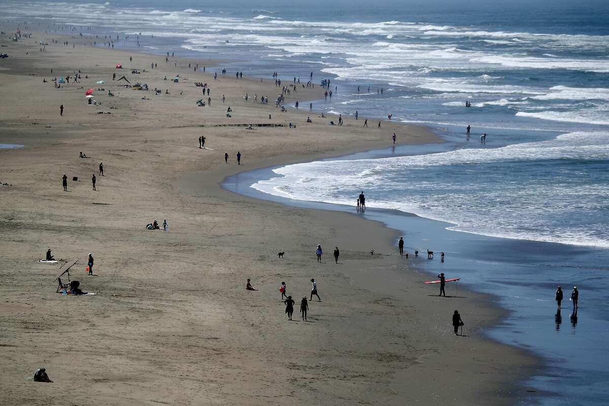 People walk along Ocean Beach on May 26, 2020 in San Francisco. The spread of the coronavirus may be contained during the summer as people spend more time outdoors, experts say.