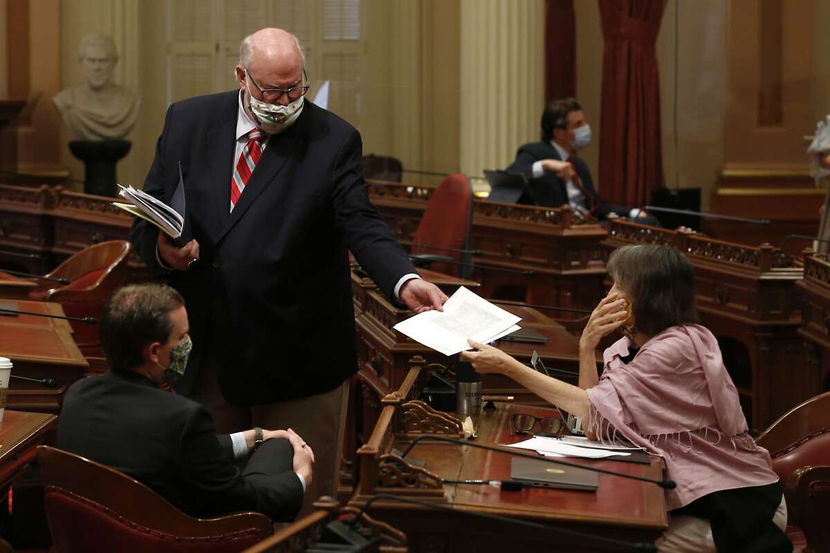 Democratic state Senators, Mike McGuire, of Healdsburg, left, Jim Beal, of San Jose, center, and Nancy Skinner, of Oakland, members of the Senate Budget and Fiscal Review Committee, huddle after a hearing on the state budget, in Sacramento, Calif., Friday, June 12, 2020. The state Legislature faces a deadline of midnight Monday, June 15, 2020 to pass the spending bill and submit it to Gov. Gavin Newsom. (AP Photo/Rich Pedroncelli)