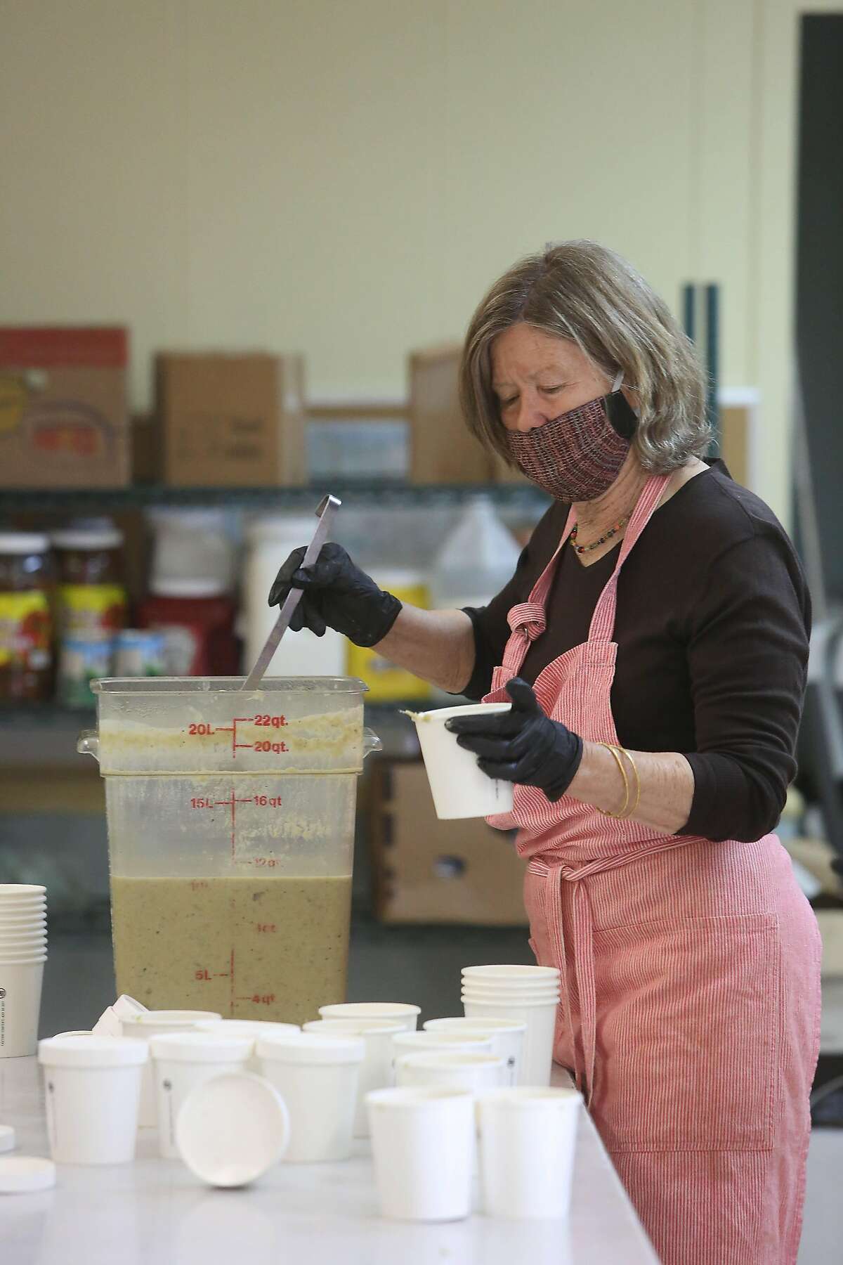 Anne Hatch, Food Runner volunteer, prepares food for delivery as she works in the new Food Runners’ kitchen at the Waller Center in San Franciscon Monday, April 20, 2020 in San Francisco, Calif.