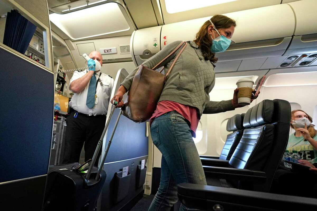 A passenger wears a mask while boarding a United Airlines flight at George Bush Intercontinental Airport Sunday, May 24, 2020, in Houston. Fewer people are flying this Memorial Day holiday amid the COVID-19 coronavirus pandemic.