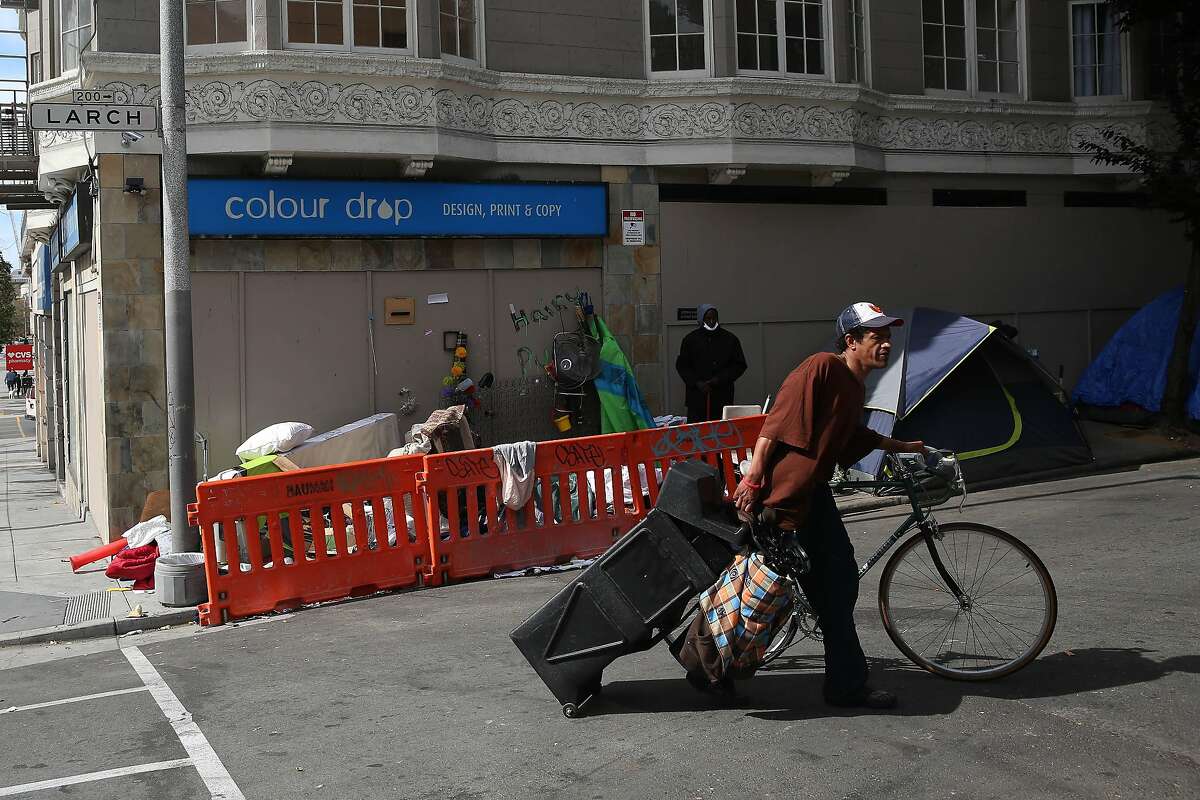 A man drags a bin as he walks a bicycle along Larch Street on Monday, June 15, 2020 in San Francisco, Calif.