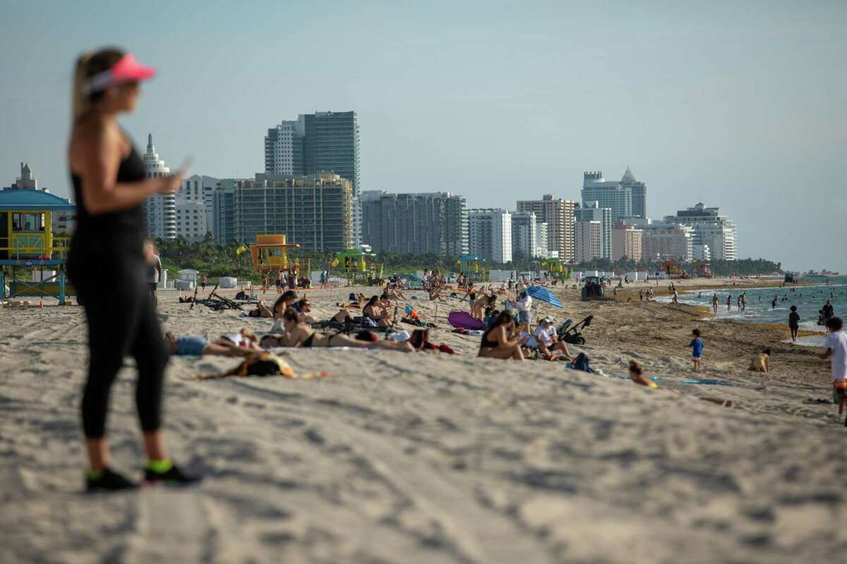 People sit on the beach in Miami Beach on June 10. 2020.