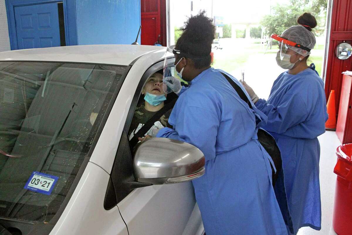 Medical assistants Fetechia Robinson, left, and Victoria Arocha administer a coronavirus test to a driver at the Vehicle Inspection Station on Austin Highway.