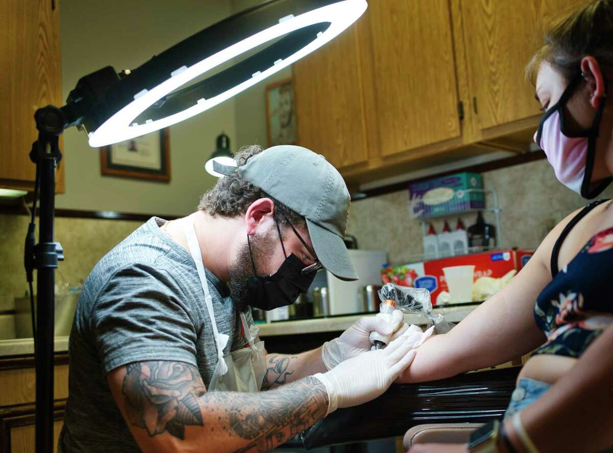 Tattoo artist Elija Ortiz inks medical alert symbol on the wrist of Sadie Dunne of Albany at Tom Spaulding Tattoo and Body Piercing Studio on Wednesday, June 17, 2020, in Albany, N.Y. Wednesday was the first day that tattoo shops could reopen for business. (Paul Buckowski/Times Union)