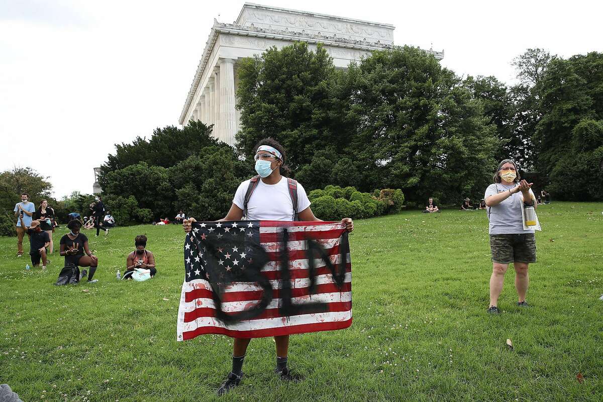 WASHINGTON, DC - JUNE 06: A demonstrator standing at the Lincoln Memorial holds an American flag with "BLM" painted on it during a protest against police brutality and racism on June 6, 2020 in Washington, DC. This is the 12th day of protests with thousands of people descending on the city to peacefully demonstrate in the wake of the death of George Floyd, a black man who was killed in police custody in Minneapolis on May 25. (Photo by Win McNamee/Getty Images)