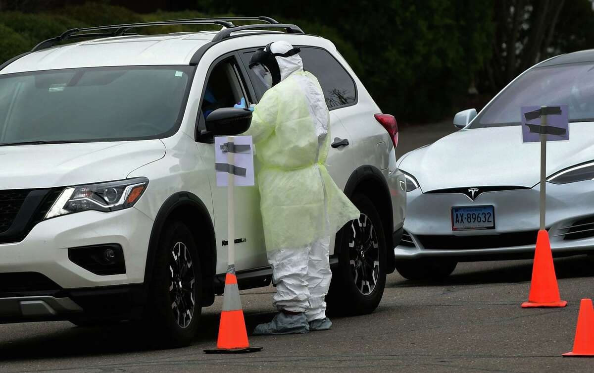 Workers with Murphy Medical Associates conduct corona virus at a drive-thru testing station Tuesday, March 31, 2020, at Bedford Middle School in Westport, Conn. Due to a large coronavirus outbreak in Westport, the Westport Weston Health District arranged for additional community testing. Residents of Westport and Weston were tested by Murphy Medical Associates, a private company, from 8:30 a.m. to noon.