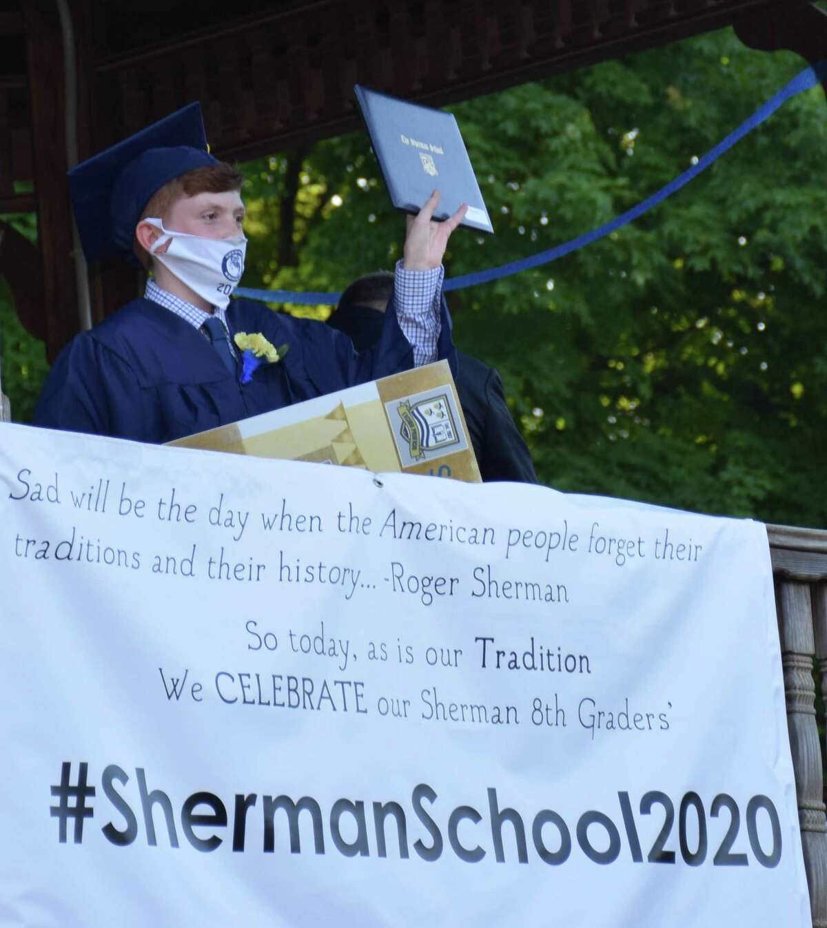 Justin Ruffler proudly holds up his certificate to his classmates parked in vehicles in Veterans Field.
