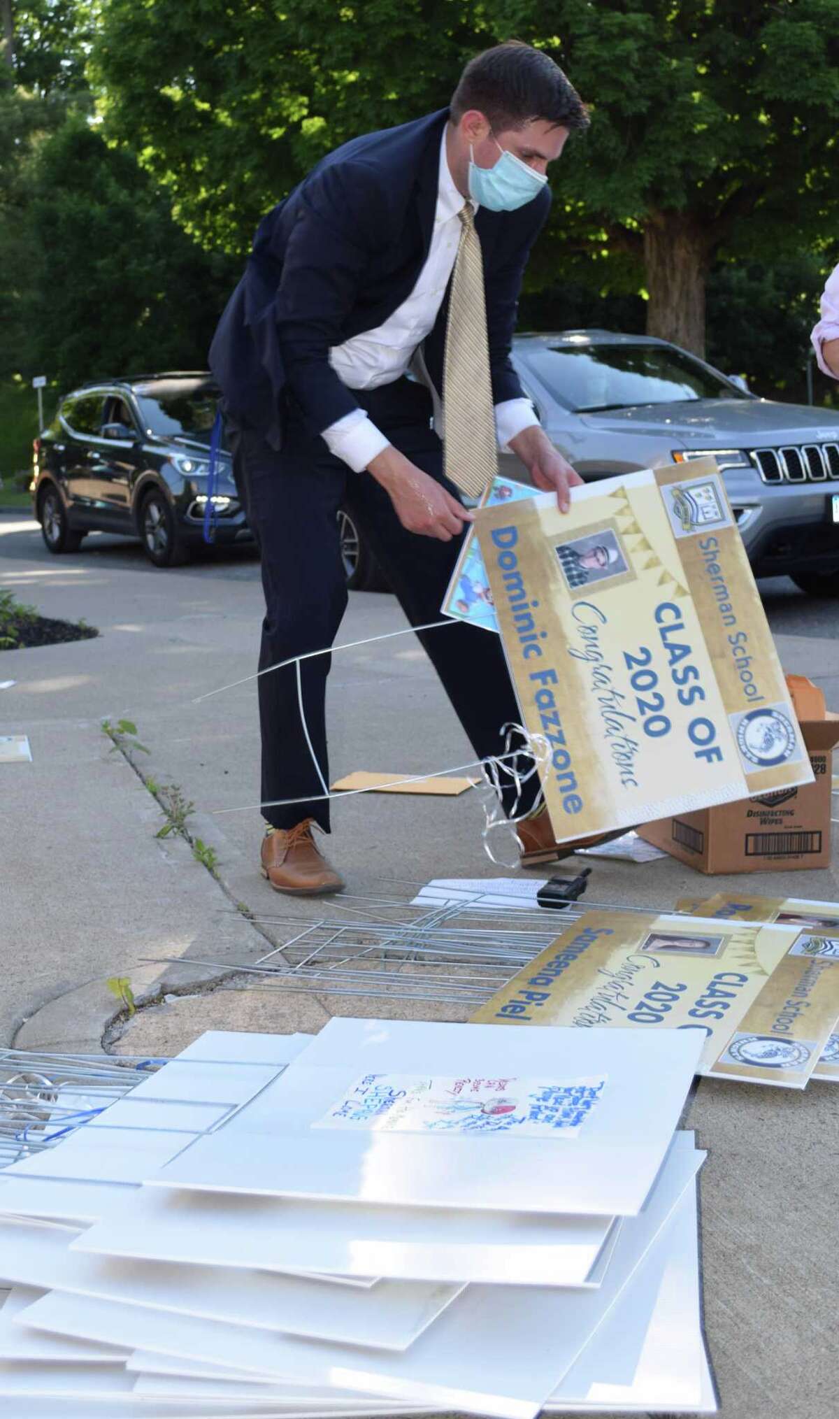 Sherman School Assistant Principal Brian Kalkreuth organizes the lawn signs given to students to hold up at the ceremony and then take home.