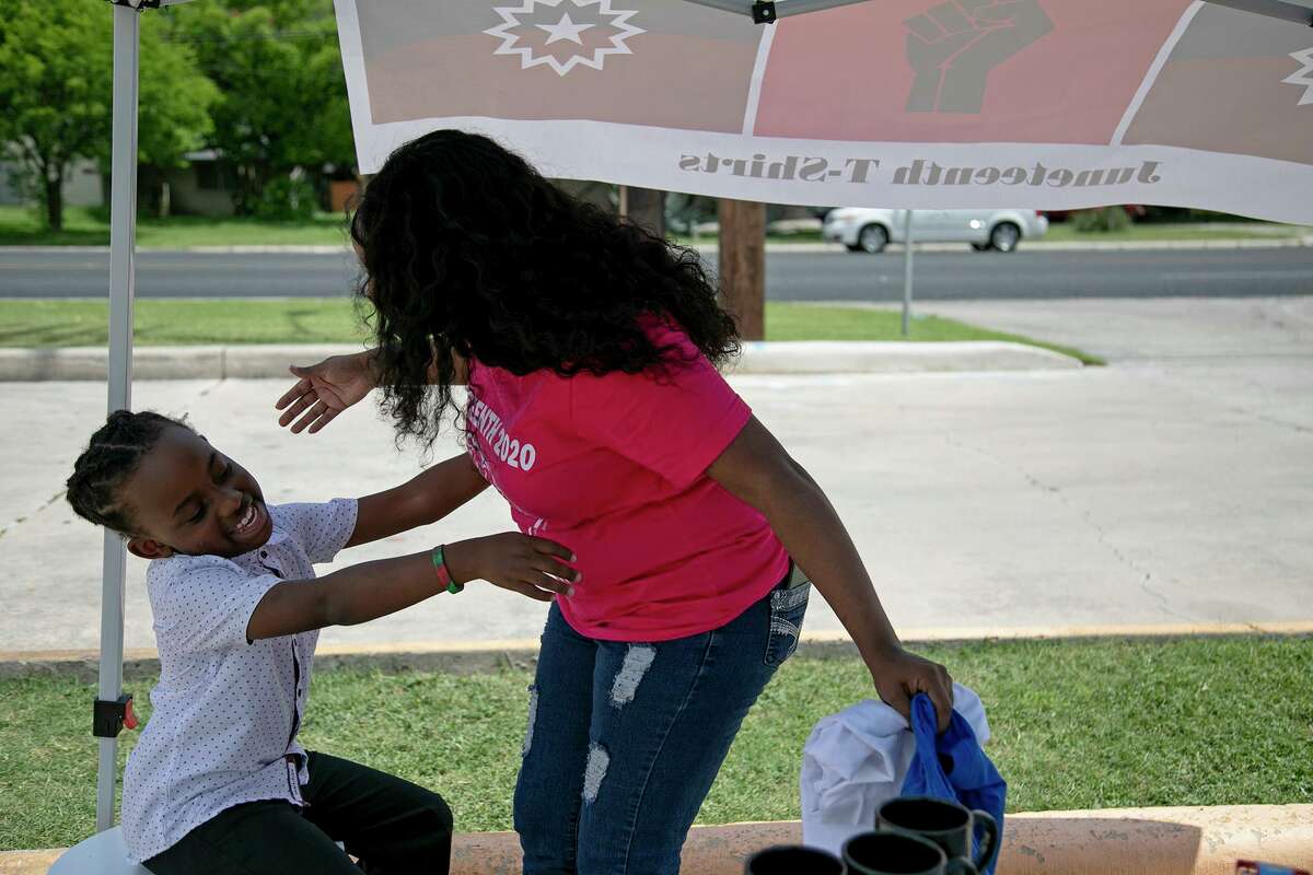 Tye Alderman, 10, embraces his mother, Kierra Alderman, as she leaves the tent where her family is selling Juneteenth and Empowerment shirts and “movement mugs” to make deliveries to customers in San Antonio on Tuesday, June 16, 2020.