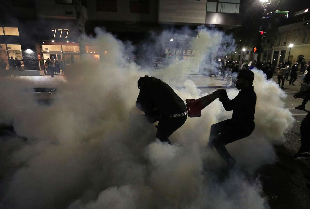 OAKLAND, CALIFORNIA - MAY 29: A demonstrator attempts to cover a tear gas canister that was deployed by police officers during a protest sparked by the death of George Floyd while in police custody on May 29, 2020 in Oakland, California. Earlier today, former Minneapolis police officer Derek Chauvin was taken into custody for Floyd's death. Chauvin has been accused of kneeling on Floyd's neck as he pleaded with him about not being able to breathe. Floyd was pronounced dead a short while later. Chauvin and 3 other officers, who were involved in the arrest, were fired from the police department after a video of the arrest was circulated. (Photo by Justin Sullivan/Getty Images)