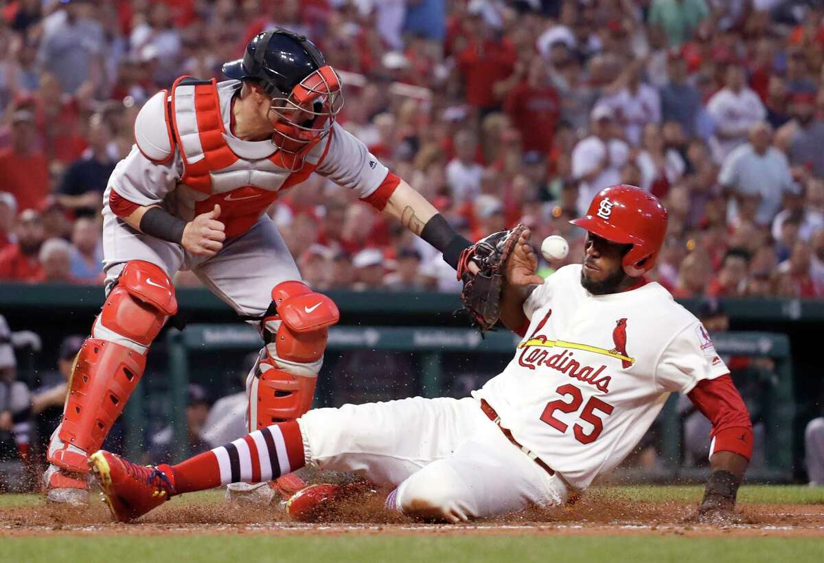 FILE - In this May 16, 2017, file photo, St. Louis Cardinals' Dexter Fowler (25) scores as Boston Red Sox catcher Christian Vazquez is unable to catch the ball during the third inning of a baseball game in St. Louis. Most of the games played between the Red Sox and Cardinals have been in the World Series. If not for the coronavirus pandemic, they would have been playing a regular-season series next weekend at Fenway Park. (AP Photo/Jeff Roberson, File)