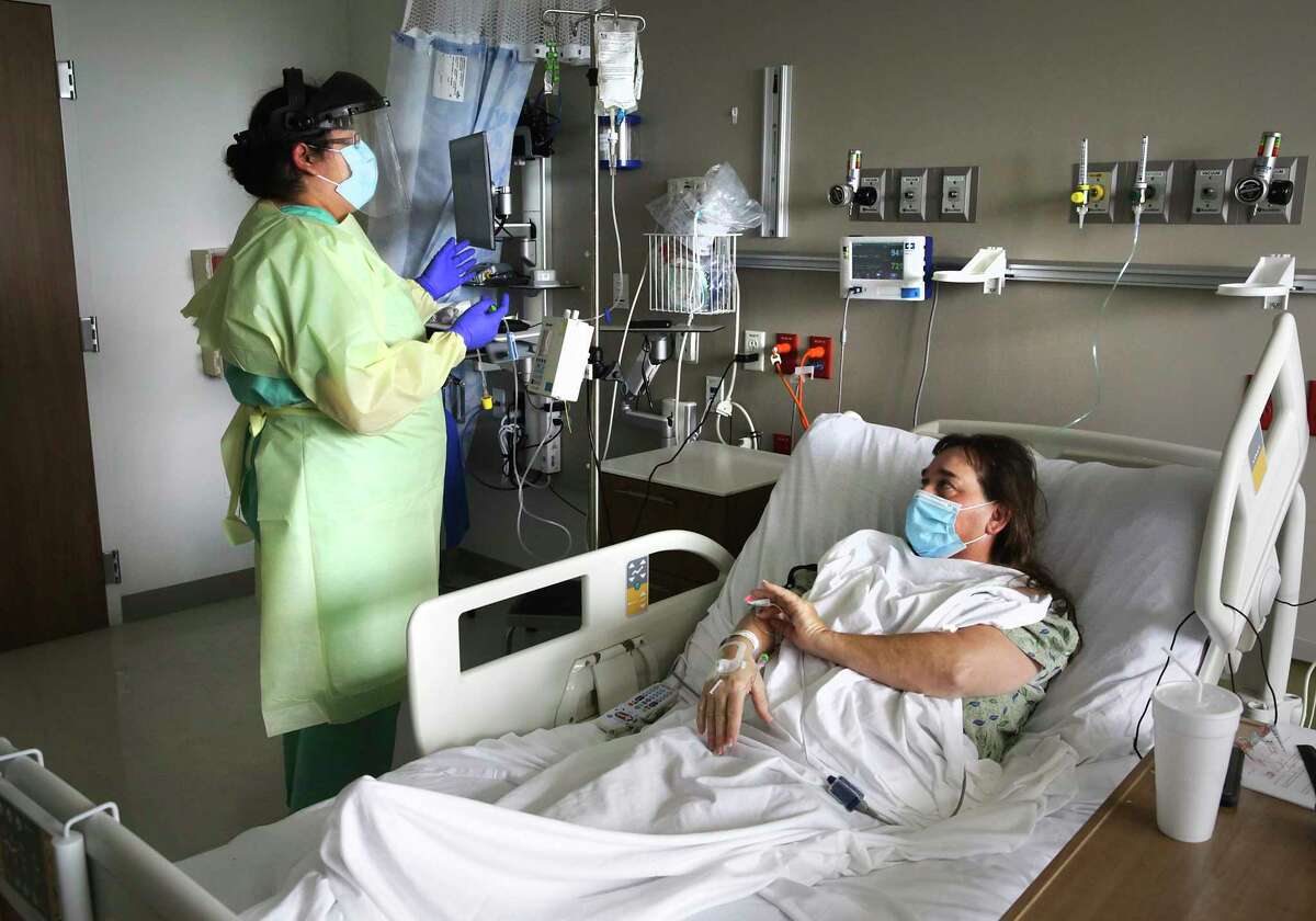 Nurse Olivia Rocha, left, administers the antiviral drug remdesivir to COVID-19 patient Betty Talton at University Hospital.