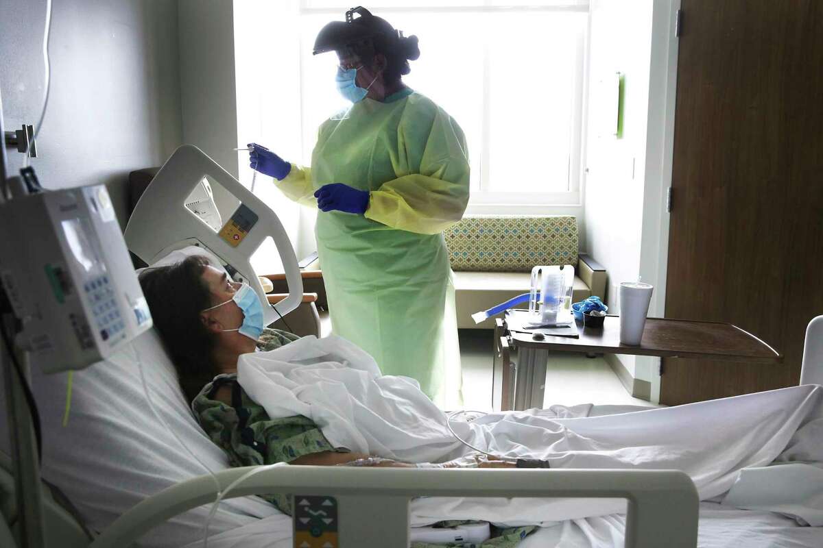 Nurse Olivia Rocha prepares to take the temperature of coronavirus patient Betty Talton at University Hospital in June.