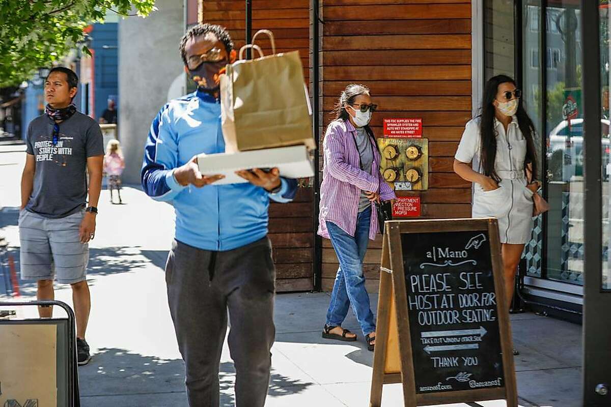 People wear masks as they walk through Hayes Valley on, June 17, 2020 in San Francisco.