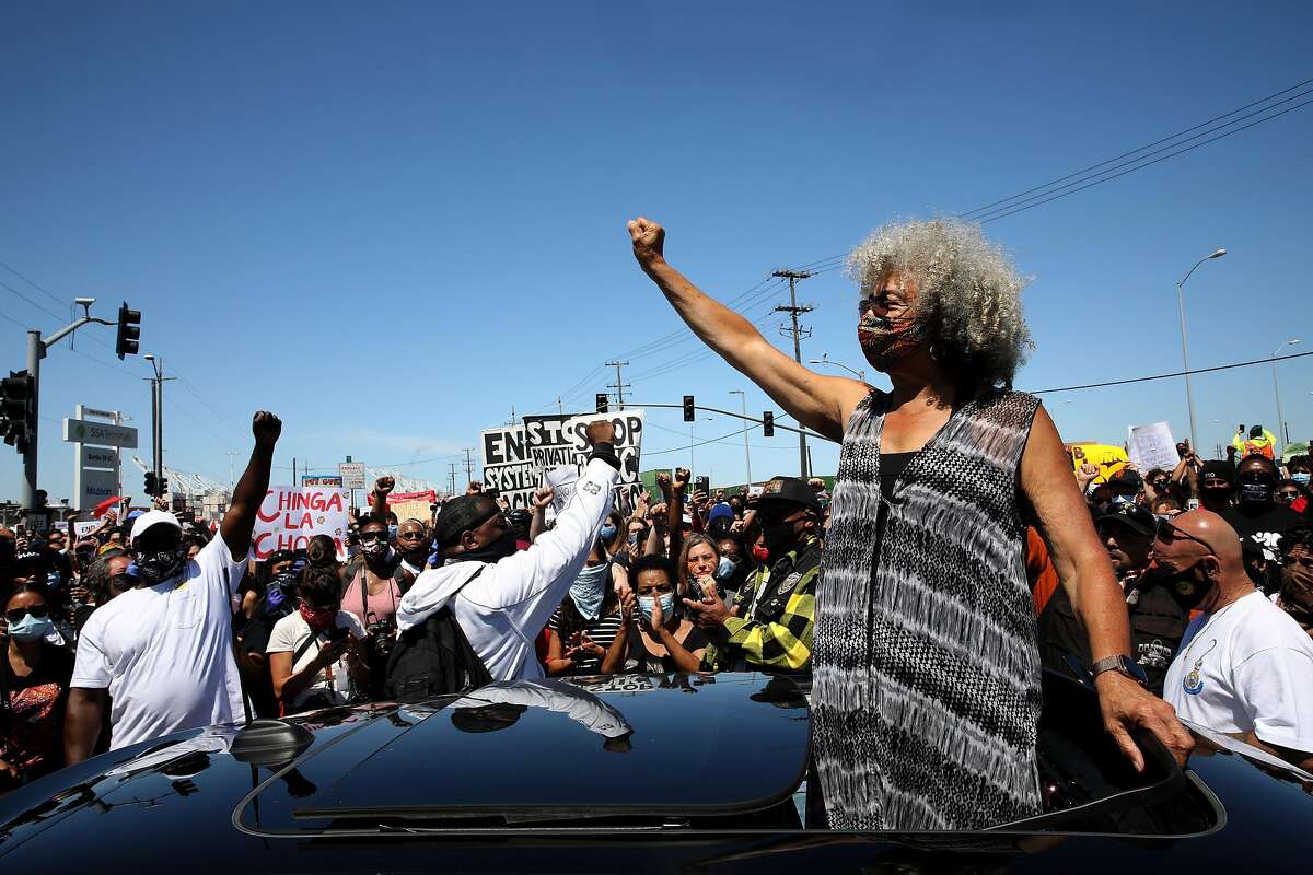 2020年6月19日星期五，在加利福尼亚州奥克兰，码头工人关闭了奥克兰港和西海岸其他28个港口，民权偶像安吉拉·戴维斯在抗议警察暴行的六月节抗议活动中挥舞着拳头。