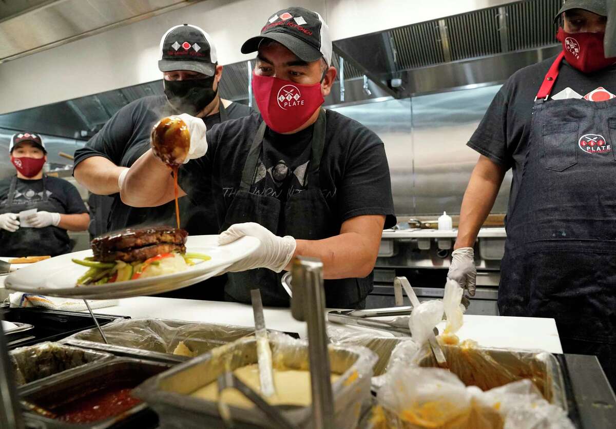 Eduardo Francisco garnishes a plate as he and others all wear masks as they work at The Union Kitchen, 9920 Gaston Road, on Thursday in Katy.