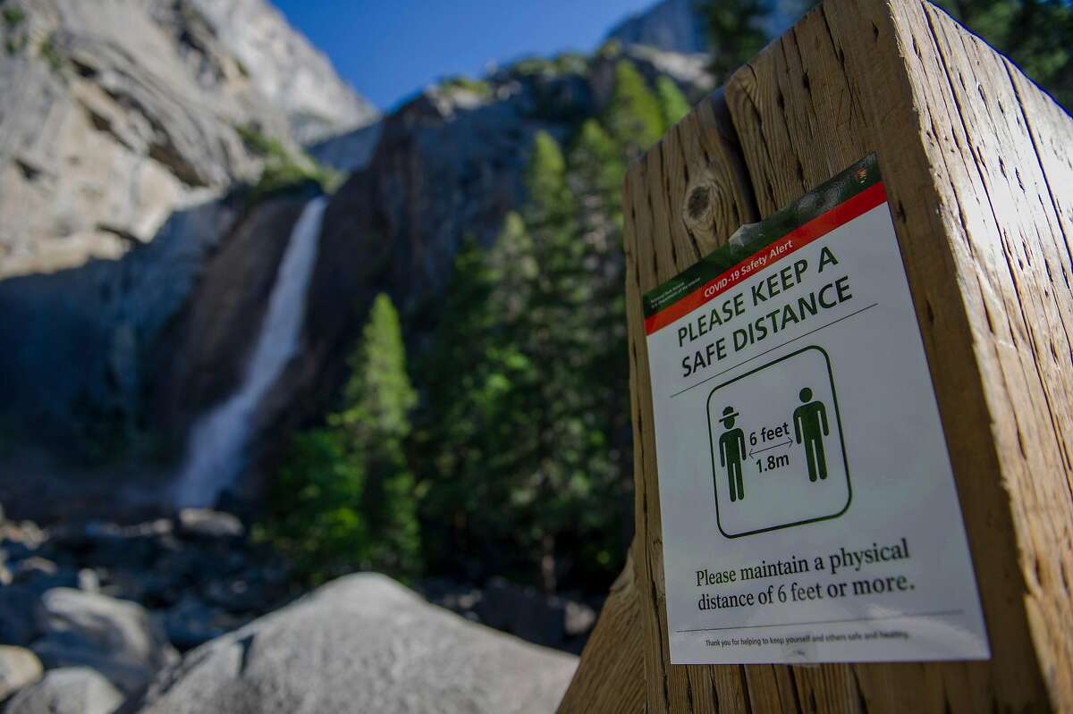Physical distancing signs are placed throughout Yosemite National Park, here at Yosemite Falls, on Thursday, June 11, 2020.