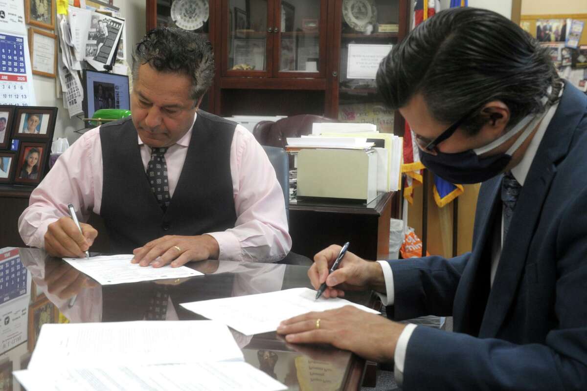 Ansonia Mayor David Cassetti, left, and Corporation Counsel John Marini sign legal documents turning over four downtown city properties to Shaw Growth Ventures of New York. Shaw plans to renovate the properties into at least 300 apartments on the upper floors and retail on the lower within five years after receiving permit approvals. .