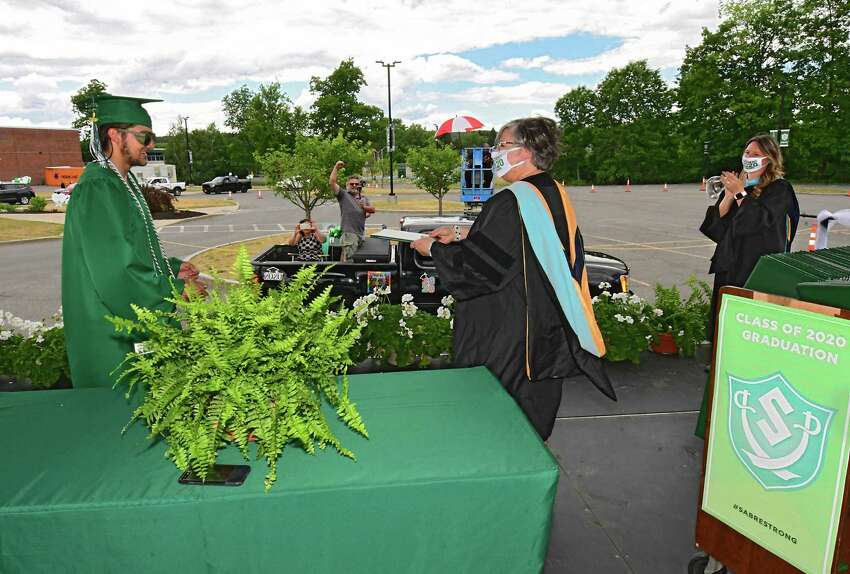 Graduate Dillon DiGirolamo receives his diploma from Superintendent Dr. Carol Pallas as graduates pick up their diplomas during a drive through graduation at Schalmont High School on Friday, June 19, 2020 in Rotterdam, N.Y. Dillon's family records the special moment from their truck.(Lori Van Buren/Times Union)