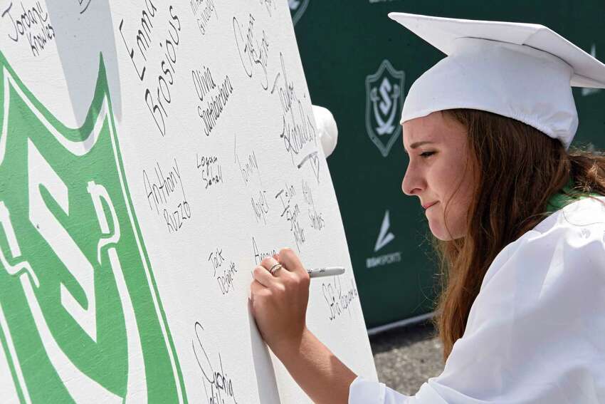 Graduate Amaya DiGiovanni signs a class poster while graduates pick up their diplomas as Schalmont Central School District holds a drive through graduation at Schalmont High School on Friday, June 19, 2020 in Rotterdam, N.Y. (Lori Van Buren/Times Union)