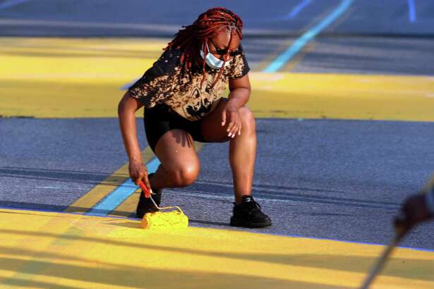 As part of the celebration of Juneteenth, Latoya Radway, of Bridgeport, takes part in painting the words "Black Lives Matter" onto Broad Street in downtown Bridgeport, Conn., on Friday June 19, 2020. The event was organized by Sheree Baldwin-Muhammad and involved local artists, community members, local officials and residents to paint the words.