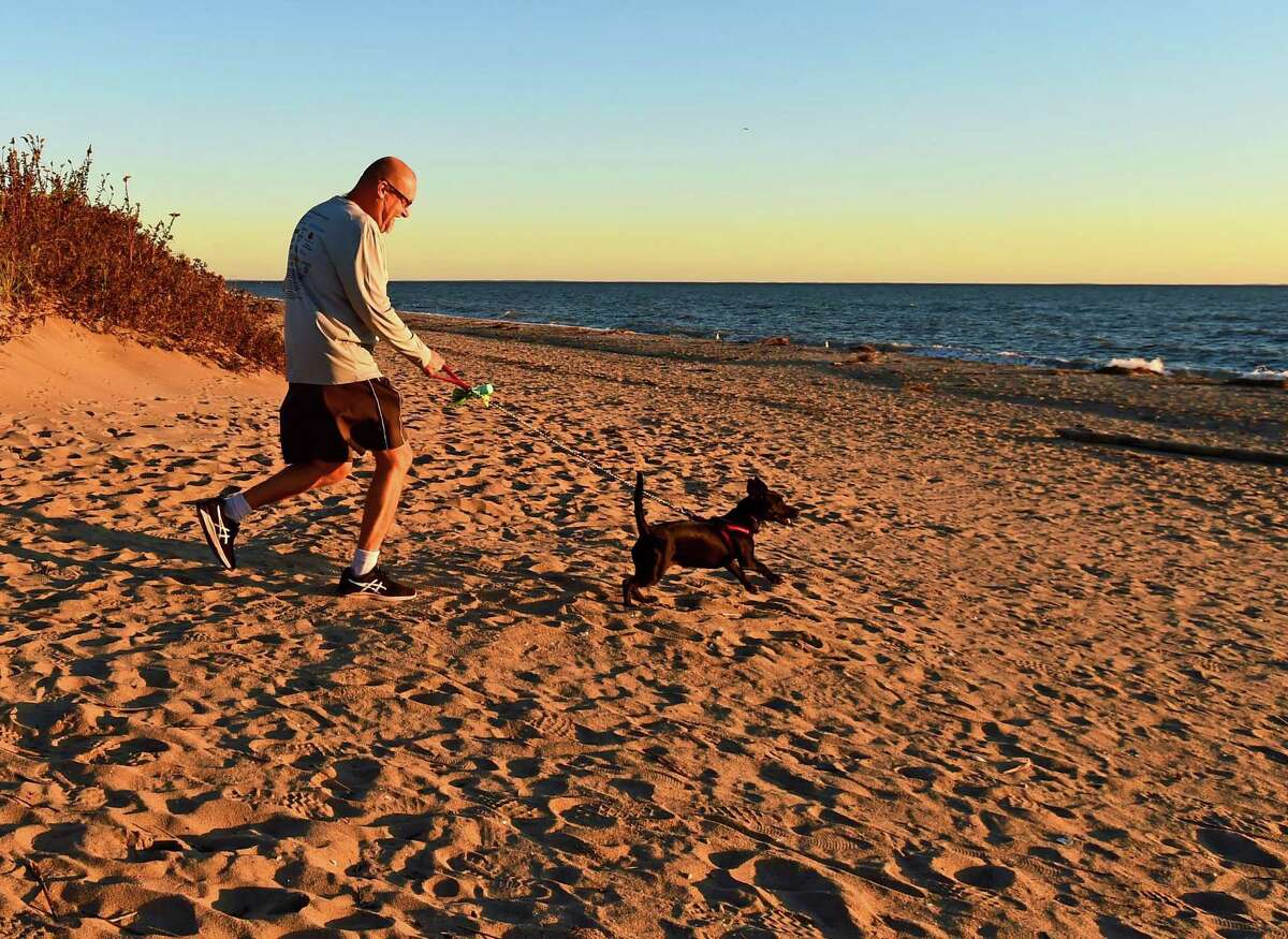 Madison, Connecticut - Wednesday, October 23, 2019: Enjoy the mild fall weather, Bob Kyrcz of Madison and his dog Brie, a Rat Terrier mix, start their evening walk on the beach Thursday at Hammonasset State Park in Madison.