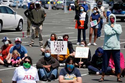 Demonstrators gather for a rally in the Golden Gate Ferry Terminal parking lot before a caravan of cars carrying more than 200 protesters drives past the west gate of San Quentin State Prison in Larkspur.