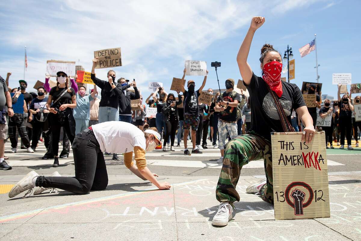 Zo‘ Zehnder, 15, of Menlo Park (right) kneels and raises her fist in front of City Hall after marching with hundreds down Market Street from the Ferry Building in solidarity with the Black Lives Matter movement, calling for the defunding of police, investment in Black communities and the resignation of President Trump held in San Francisco, Calif. Saturday, June 20, 2020.