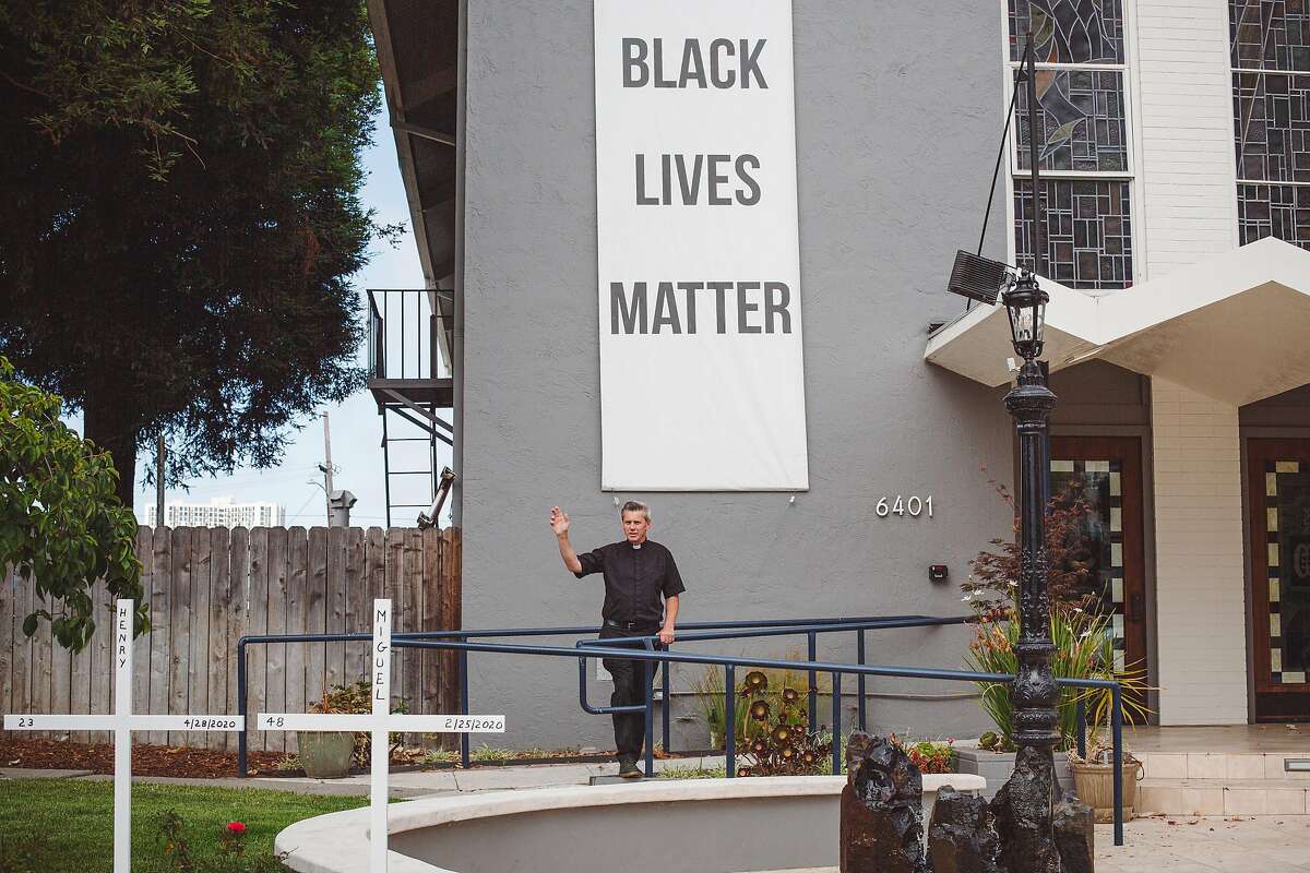 Father Aidan McAleenan stands in front of a Black Lives Matter banner at St. Columba Catholic Church in Oakland, Calif. on Friday, Jun. 19, 2020.