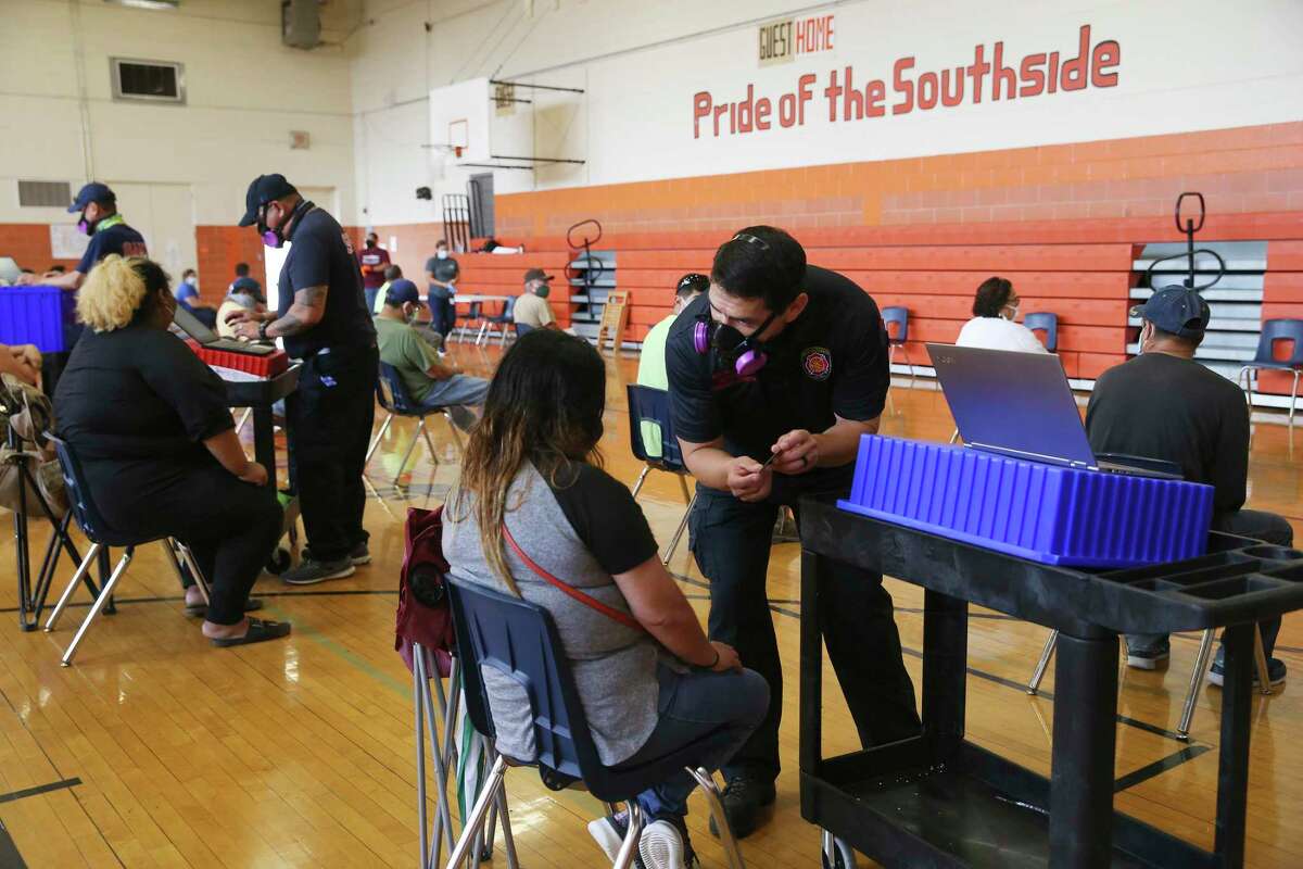 San Antonio Fire Department's Mobile Integrated Health team member John De La Garza registers people at a COVID-19 walk-up testing site at Burbank High School on Friday. The MIH team joined with San Antonio Metro Health to conduct the testing. Nearly 350 waited in line for the free test, some before 4 a.m.