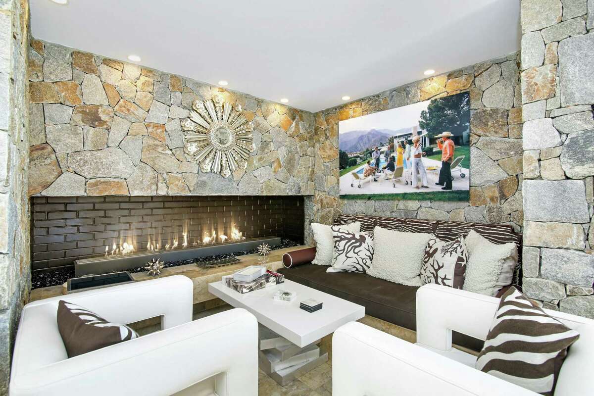 The stone wall with the fireplace in the family room creates a comfortable sitting alcove. On the main level the spacious family room features a floor-to-ceiling gas-fueled stone fireplace and a two-tiered tray ceiling with cove lighting. The living room has built-in bookshelves. The chef’s kitchen boasts Snaidero cabinetry, under cabinet lighting, upscale appliances, and a two-tiered counter with a breakfast bar for four stools. There is also a service area for catering staff when entertaining. Rounding out the main level is the office with a fireplace flanked by built-ins shelving, and two bedrooms.