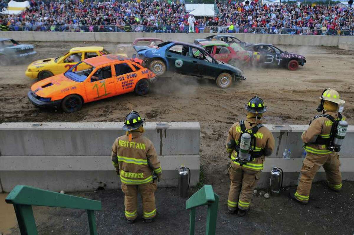 West Fort Ann firefighters stand by Monday night as the second heat of the Demolition Derby gets under way at the Washington County Fair in Greenwich. ( Philip Kamrass / Times Union )