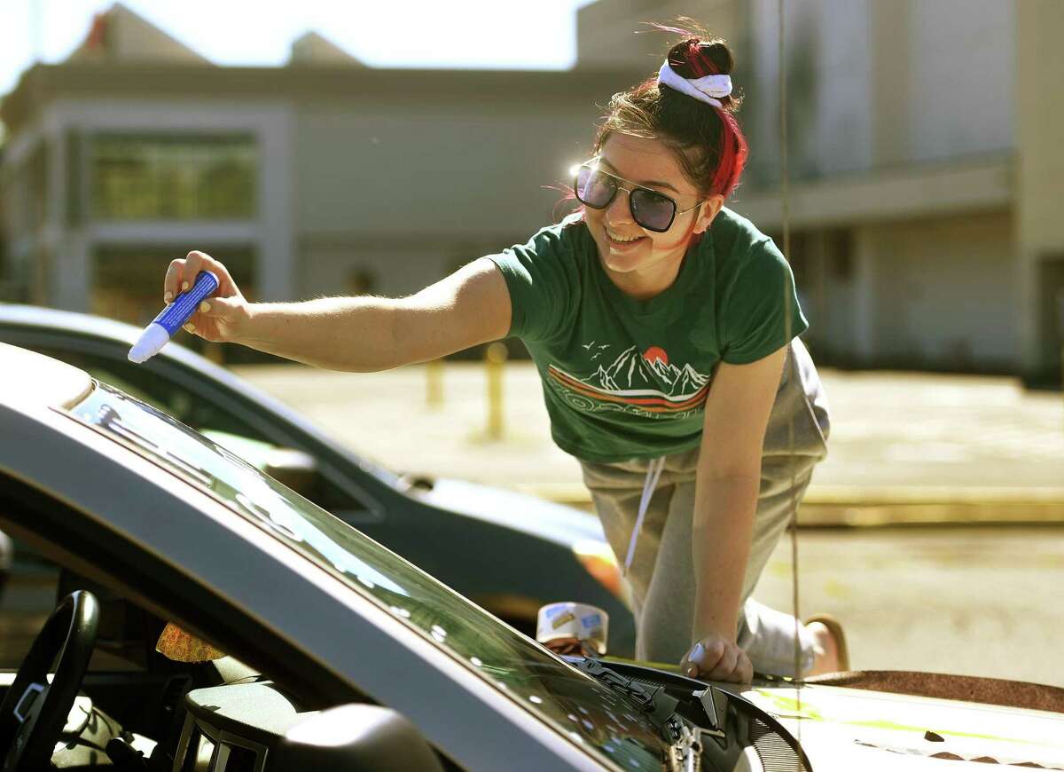 Trumbull High School 2020 graduate Kristina Franco decorates the windshield of her car for the Trumbull Eagles FlyThru street procession from the Westfield Trumbull Mall in Trumbull, Conn. on Sunday, June 21, 2020.