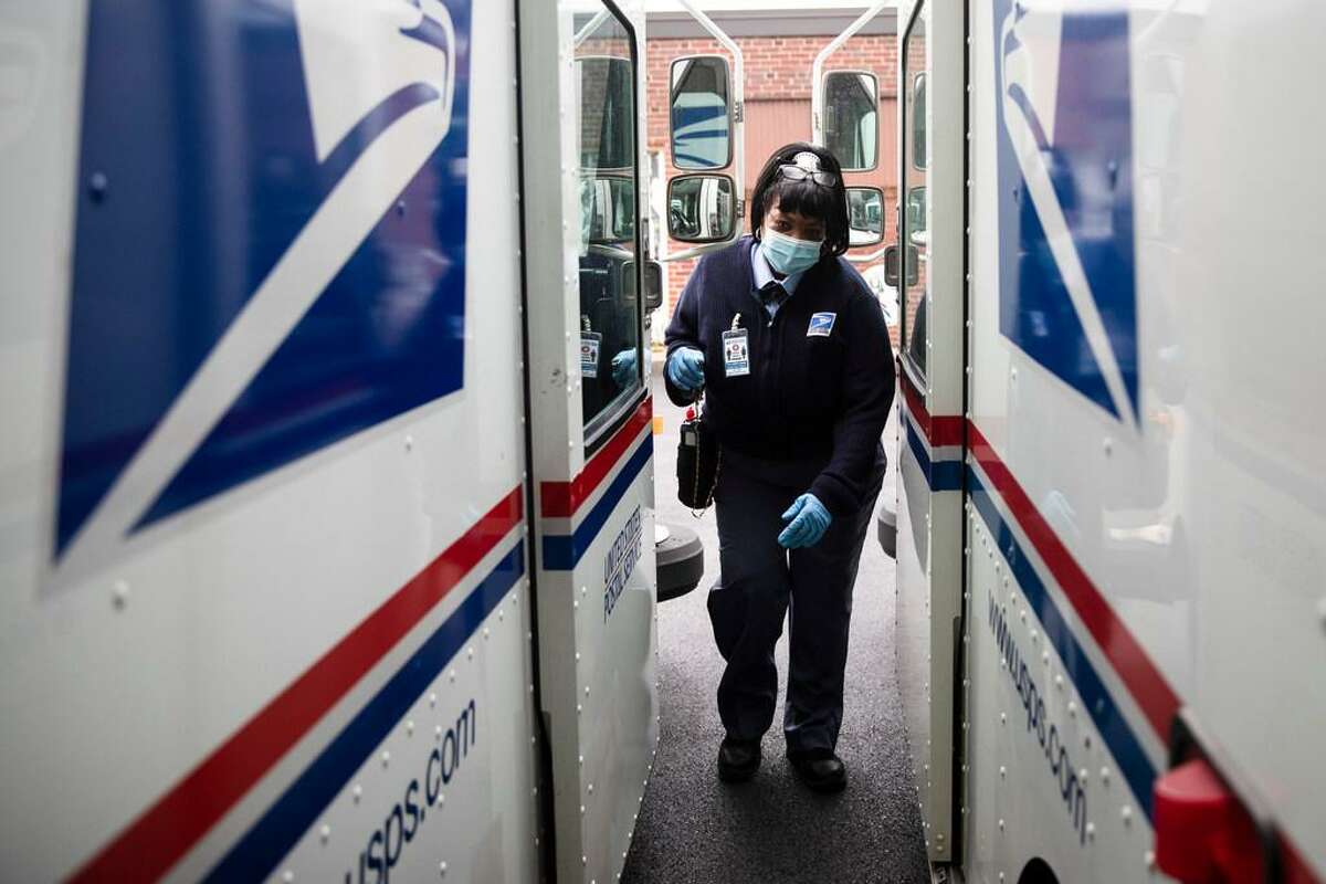 In this Wednesday, May 6, 2020, photo, United States Postal Service carrier Henrietta Dixon gets into her truck to deliver mail in Philadelphia.