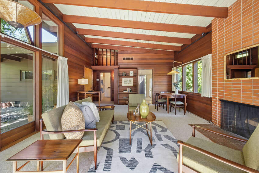 The original hearth stands ready to warm the space created by the vaulted ceiling. The mid-century wood paneling and brick are all preserved.