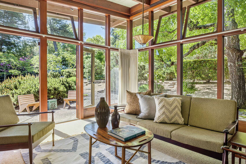 The home is preserved mid-century. Glass surrounds the living space, which looks out on almost an acre of land that the home rests on.